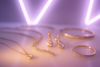 Lightly blurred aesthetic image of elegant jewellery items such as necklaces, earrings, and bracelets displayed on a soft, glowing surface. The background features a white and light purple neon theme, creating a dreamy and luxurious vibe. The blur adds a gentle focus effect that highlights sparkle, sophistication, and elegance — perfect for a modern jewellery collection display